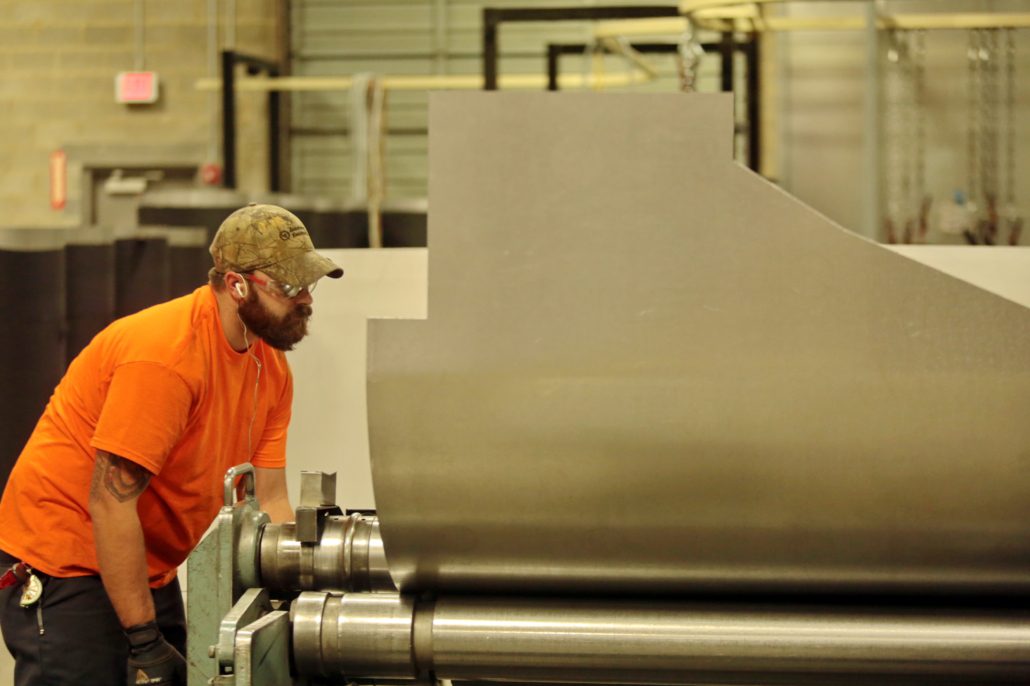A CHUTES International employee in the shop working with a metal roller